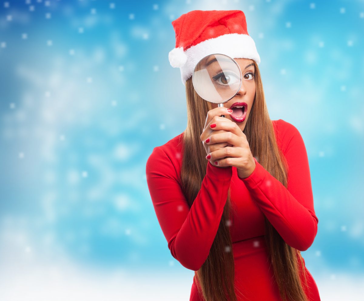 portrait of a beautiful young woman looking through the magnifying glass at Christmas
